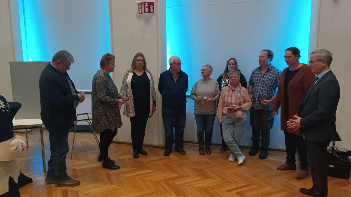 Das Foto zeigt Bürgermeister Igel zusammen mit ehrenamtlich Engagierten im Saal des Klubhauses Ludwigsfelde.
