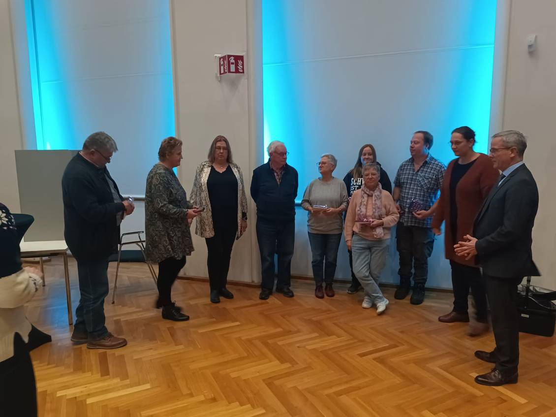 Das Foto zeigt Bürgermeister Igel zusammen mit ehrenamtlich Engagierten im Saal des Klubhauses Ludwigsfelde.