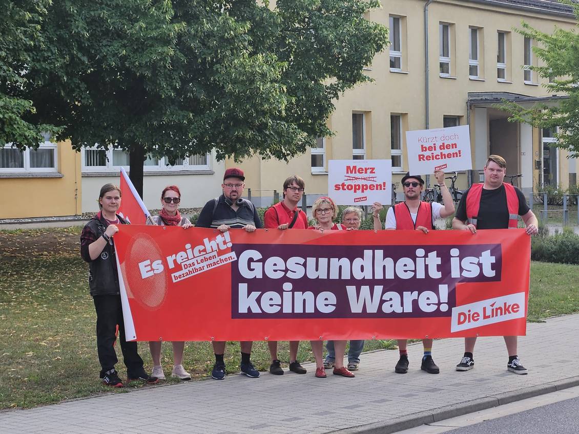Das Foto zeigt mehrere Personen mit einem Banner, darauf die Worte "Gesundheit ist keine Ware!"