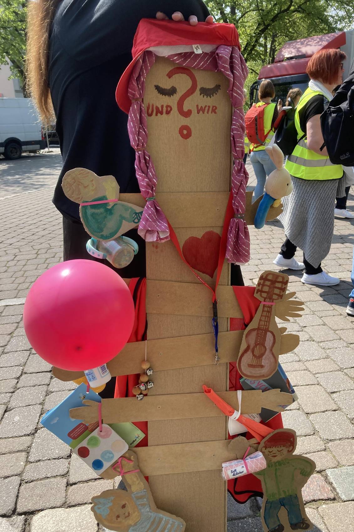 Selbst gebastelte Puppe mit mehreren Armen, an denen Gegenstände aus einer Kita hängen, auf der Streikkundgebung am 4. Mai 2022 in Königs Wusterhausen