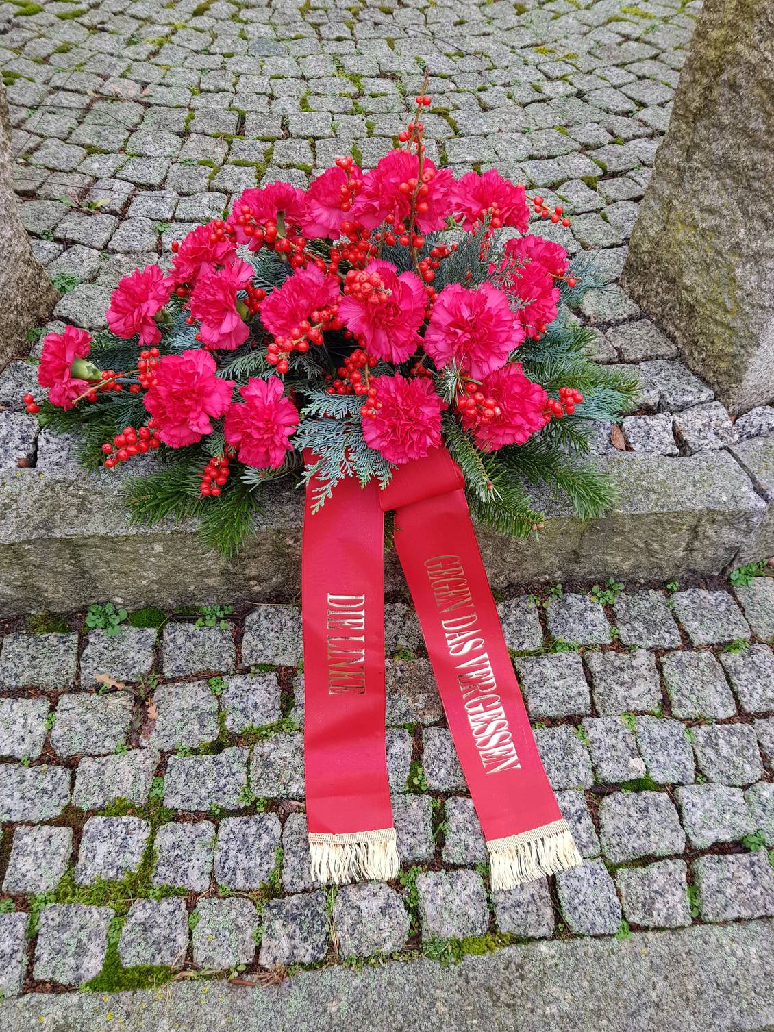 Das Foto zeigt ein Trauergebinde mit roten Nelken.