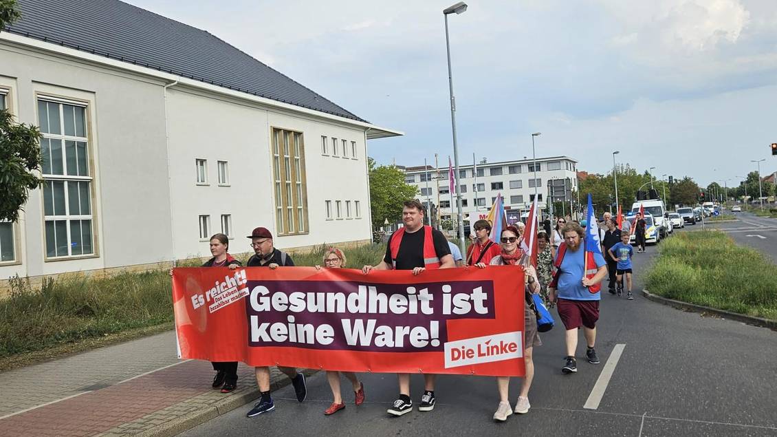 Das Foto zeigt mehrere Personen bei einer Demo auf einer Straße.